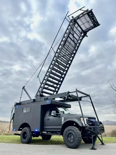Blacked-out Super Duty service body with a hydraulic tactical entry ladder deployed on outriggers